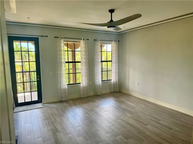 Empty room featuring a wealth of natural light, hardwood / wood-style flooring, ceiling fan, and crown molding