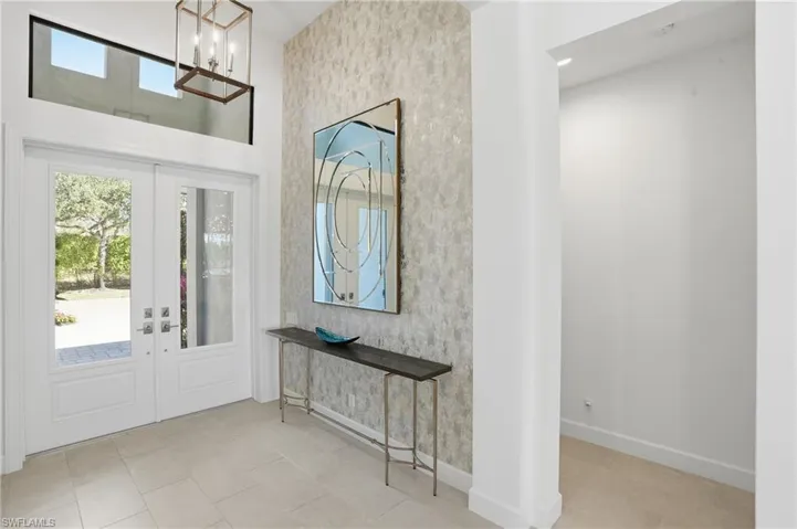 Entrance foyer with french doors and a chandelier