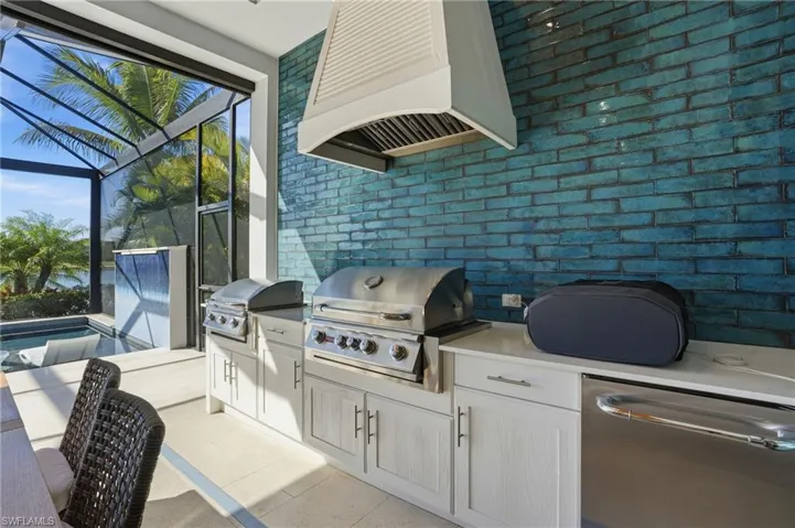 View of patio / terrace featuring glass enclosure, an outdoor kitchen, a sunroom, and an outdoor pool