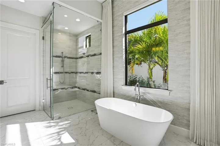 Bathroom featuring a stall shower, a freestanding tub, recessed lighting, and marble finish floors