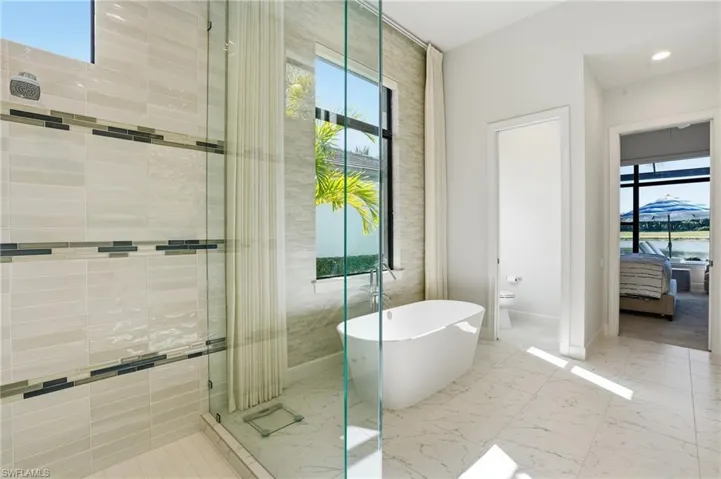 Ensuite bathroom featuring healthy amount of natural light, a freestanding tub, and a stall shower