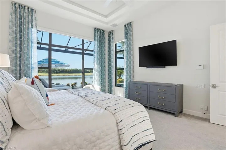 Bedroom with light colored carpet, a ceiling fan, and a tray ceiling