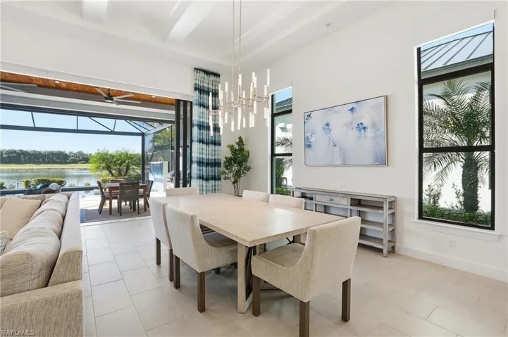 Dining space with a sunroom, a water view, light tile patterned floors, and a chandelier