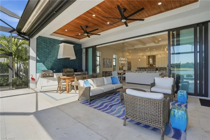 View of patio with exterior kitchen, a lanai, an outdoor living space, and ceiling fan