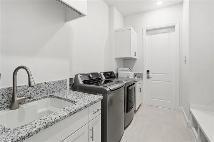 Laundry area with washing machine and clothes dryer, cabinet space, light tile patterned flooring, and recessed lighting