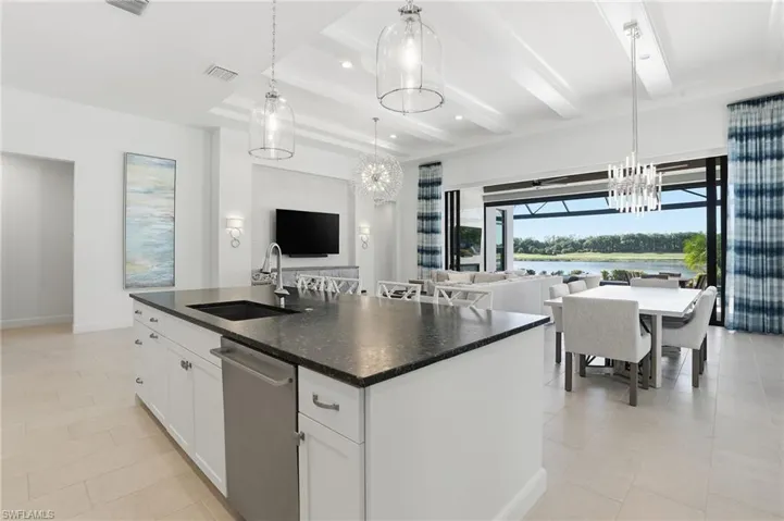 Kitchen featuring white cabinetry, a chandelier, open floor plan, an island with sink, and stainless steel dishwasher
