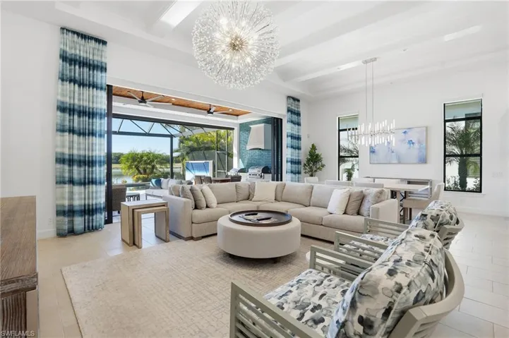 Living area featuring a chandelier, beamed ceiling, a sunroom, and plenty of natural light