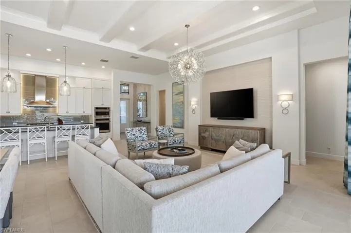 Living area with recessed lighting, a chandelier, beamed ceiling, and light tile patterned flooring
