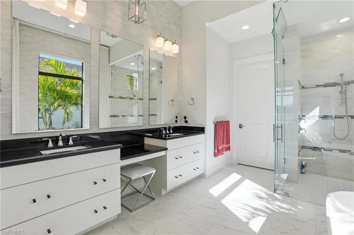 Full bathroom with double vanity, a shower stall, light marble finish flooring, recessed lighting, and a freestanding bath