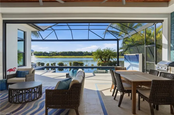 View of patio / terrace with a sunroom, outdoor dining space, glass enclosure, a water view, and area for grilling