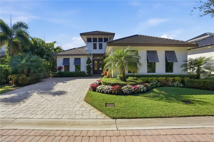 View of front facade with a front yard, decorative driveway, stucco siding, and a tiled roof