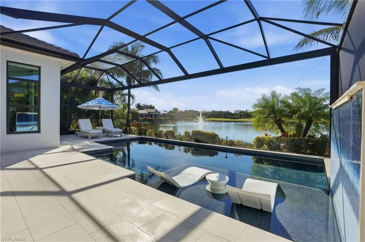Swimming pool featuring glass enclosure, a sunroom, a water view, and a patio area