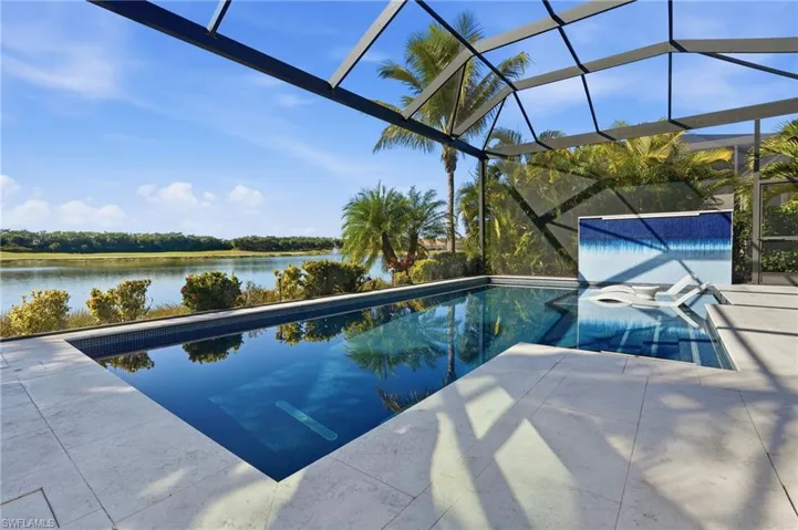 Swimming pool featuring glass enclosure, a water view, and a sunroom