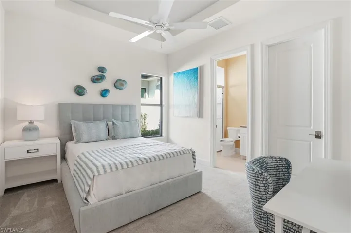 Bedroom featuring light carpet, a ceiling fan, and connected bathroom