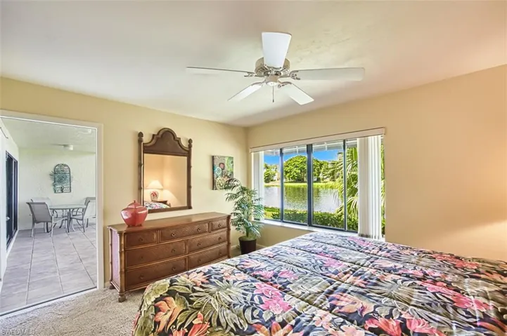 Tiled bedroom featuring a water view, carpet flooring, and a ceiling fan