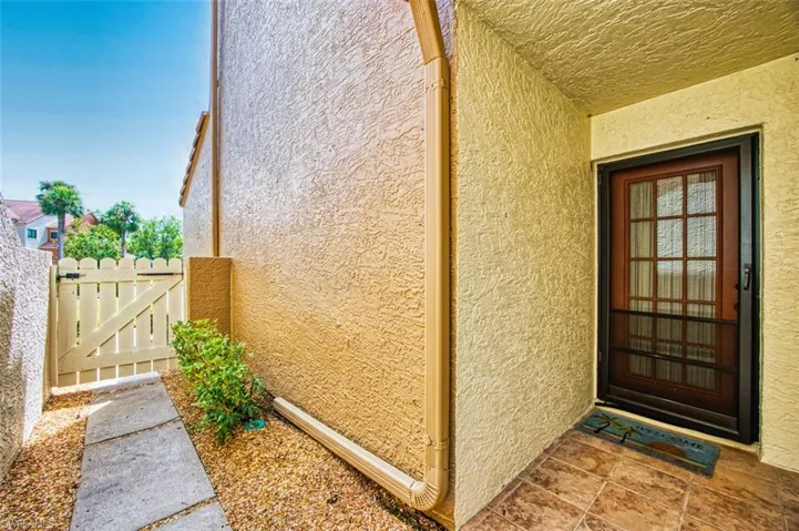 Doorway to property featuring stucco siding and a gate