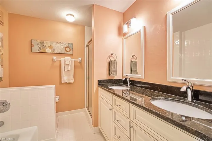 Full bath featuring light tile patterned floors, a garden tub, double vanity, and a shower stall