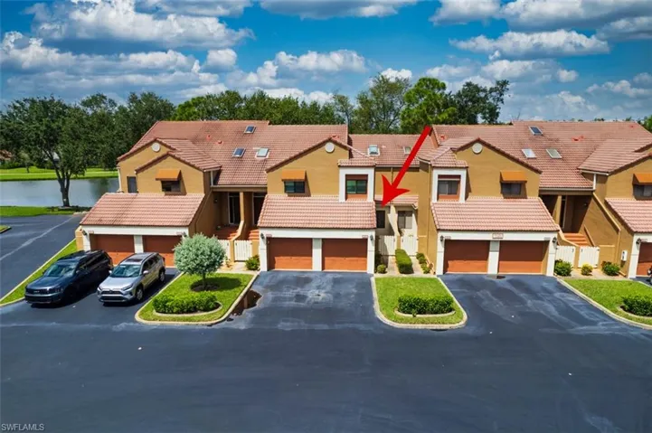 View of front of home with driveway, a water view, a tiled roof, and a garage