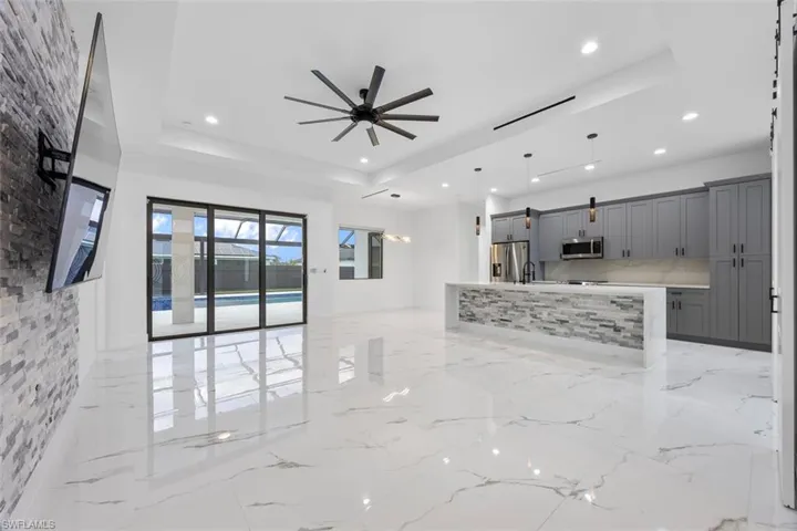 Kitchen with open floor plan, hanging light fixtures, appliances with stainless steel finishes, gray cabinets, and a raised ceiling