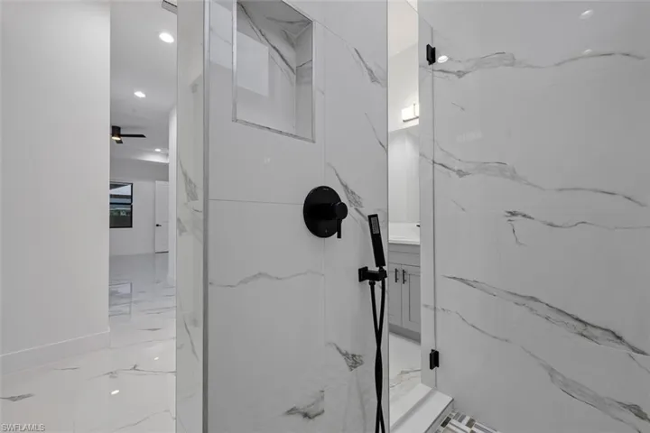Full bath featuring marble finish floor, stone wall, a marble finish shower, and recessed lighting