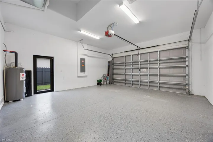 Garage with electric panel, water heater, and a garage door opener