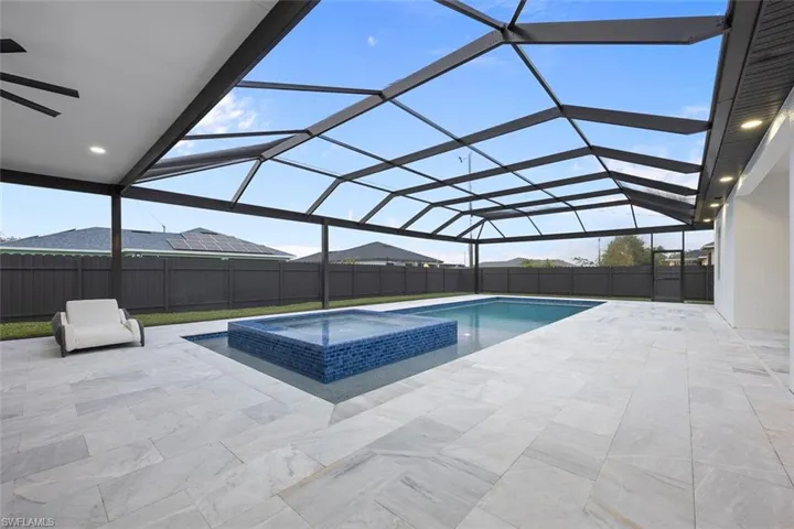 View of swimming pool with glass enclosure, a fenced backyard, a pool with connected hot tub, and a patio