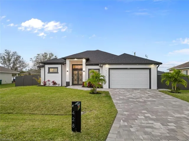 Prairie-style home with decorative driveway, an attached garage, fence, and a front yard