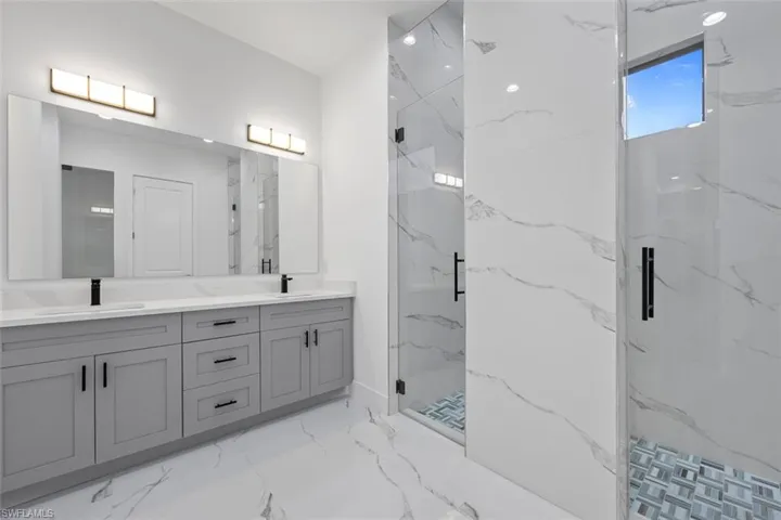Bathroom featuring marble finish floor, a sink, and a marble finish shower