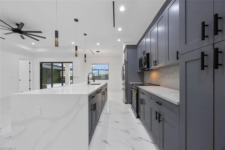 Kitchen featuring light stone counters, recessed lighting, stainless steel appliances, a spacious island, and pendant lighting