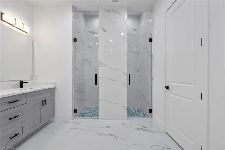 Full bath featuring marble finish floor, baseboards, vanity, and a marble finish shower