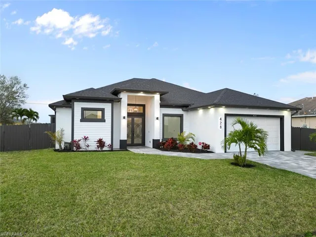 Prairie-style home featuring an attached garage, fence, a front lawn, and concrete driveway