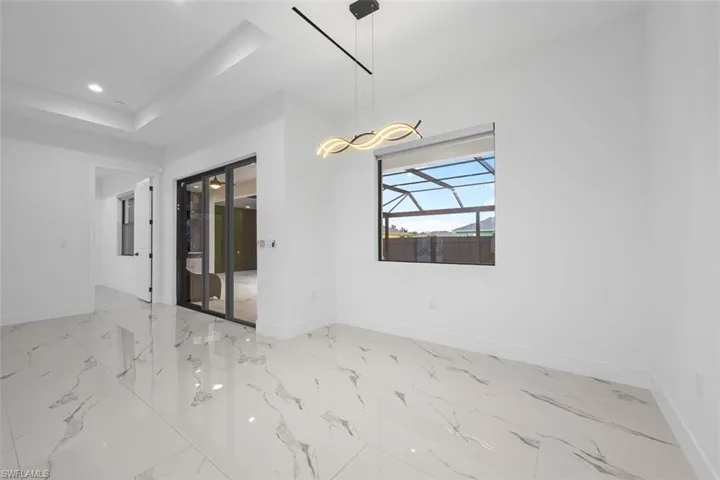 Empty room featuring baseboards, a raised ceiling, and recessed lighting
