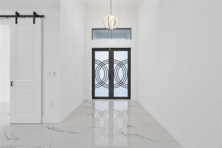 Foyer with marble finish floor, a barn door, french doors, and baseboards