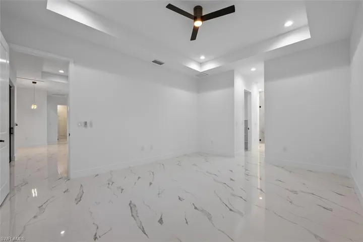 Empty room with recessed lighting, a ceiling fan, baseboards, visible vents, and a raised ceiling