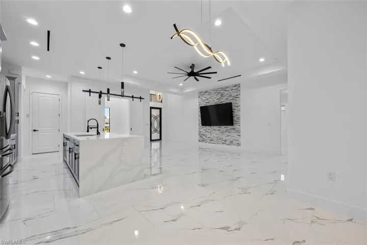 Kitchen with a barn door, an island with sink, open floor plan, hanging light fixtures, and a sink