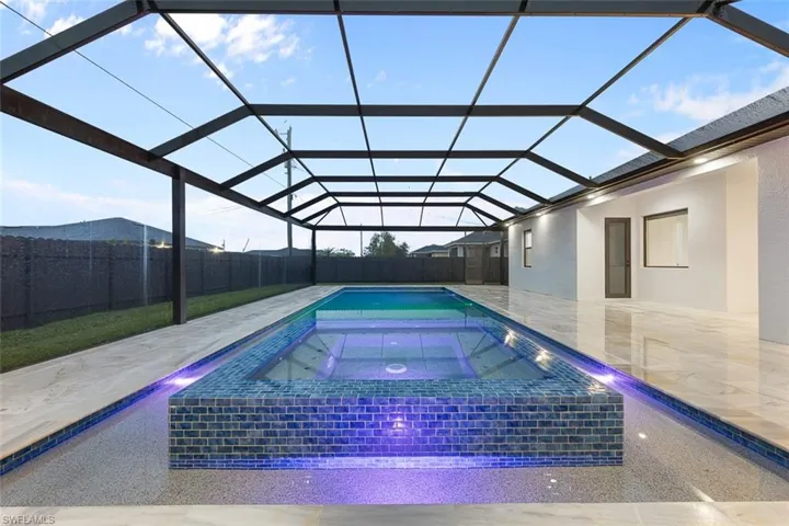 View of pool with a pool with connected hot tub, glass enclosure, a patio, and a fenced backyard