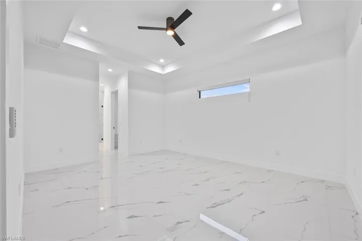 Empty room with recessed lighting, a raised ceiling, a ceiling fan, attic access, and baseboards
