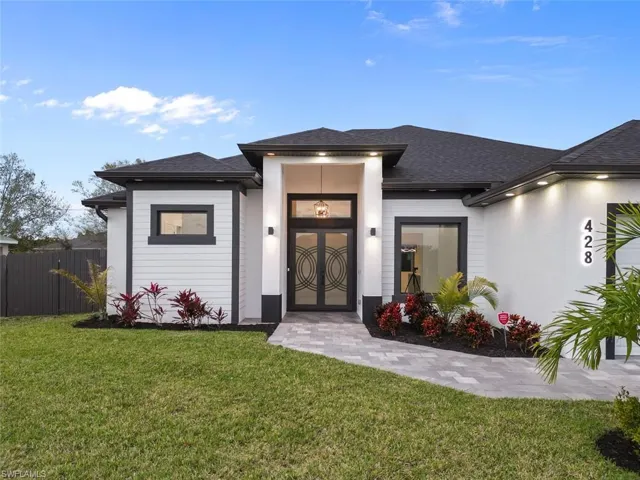 View of front of home with a shingled roof, a front yard, and fence