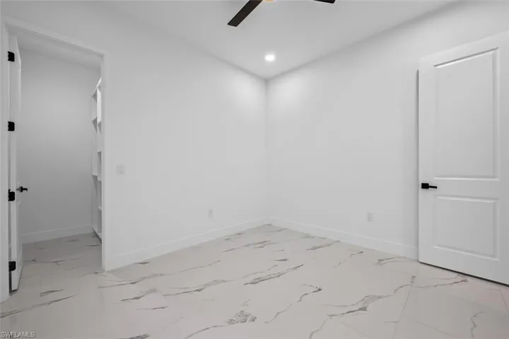 Spare room featuring marble finish floor, baseboards, a ceiling fan, and recessed lighting