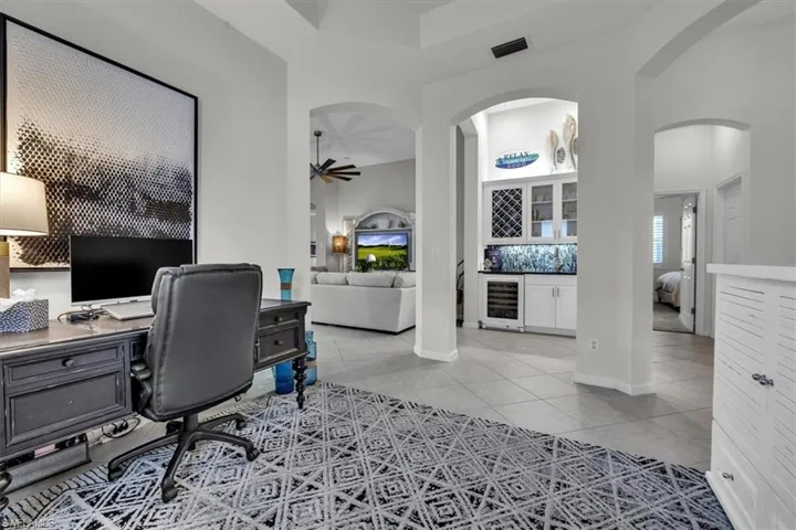 Arched doorways, tile flooring, built-in cabinetry with glass inserts, integrated wine storage, and a beverage refrigerator