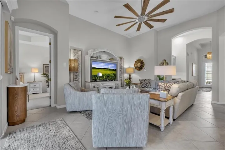 Vaulted ceiling with an overhead fan, arched doorways, tiled flooring, and light-colored walls