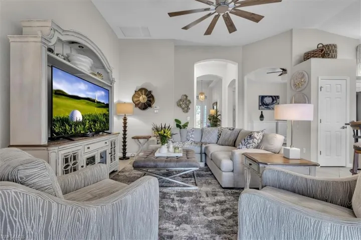 Vaulted ceilings, wood-finish ceiling fan, arched doorways, built-in entertainment center, and neutral wall tones