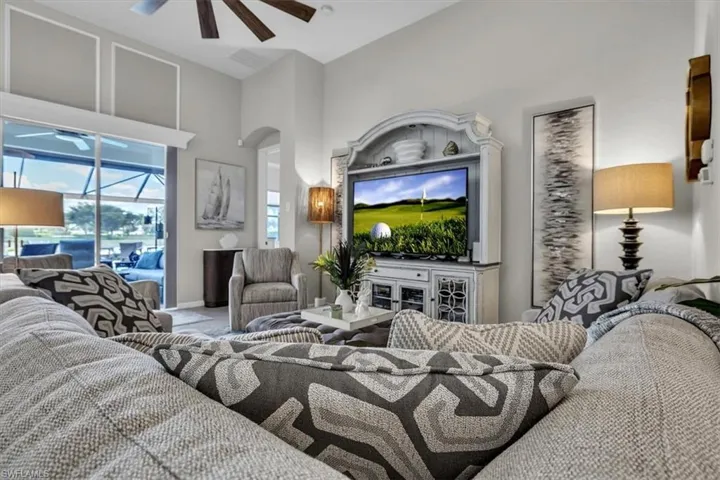 Spacious living area featuring high ceilings, a ceiling fan, and large sliding glass doors opening to an outdoor screened area
