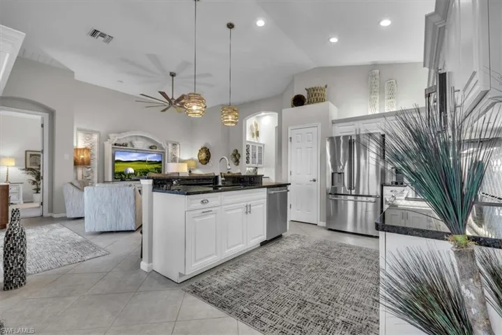 Kitchen island with white cabinetry and dark countertops, stainless steel appliances, recessed lighting, and tile flooring