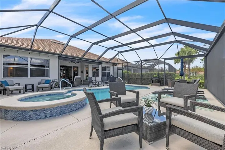 Screened lanai featuring a swimming pool, integrated spa with mosaic tile, and concrete decking