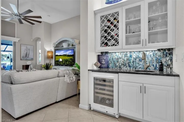 Built-in wet bar featuring white cabinetry, glass-front display cabinets, wine storage, and a beverage refrigerator