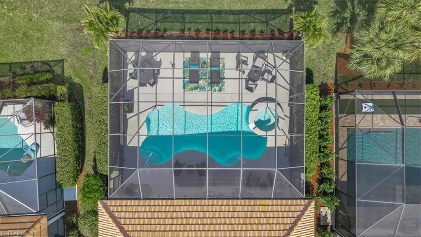 Screened pool enclosure featuring a lagoon-style pool with an integrated spa, and a surrounding paver deck