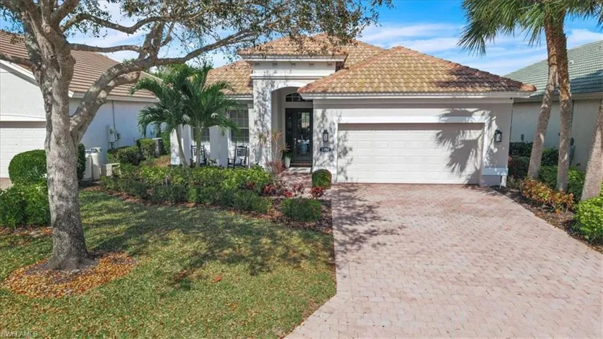 Mediterranean-inspired facade with a tiled roof, arched entryway, and an attached garage