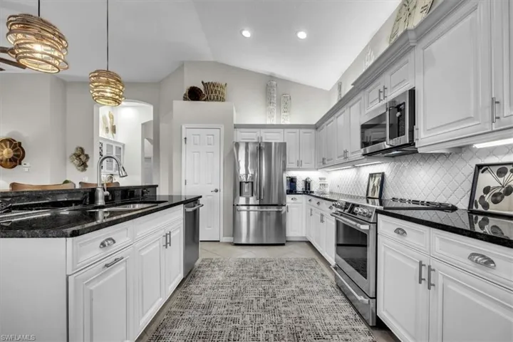 White cabinetry with dark countertops, stainless steel appliances, and a tiled backsplash
