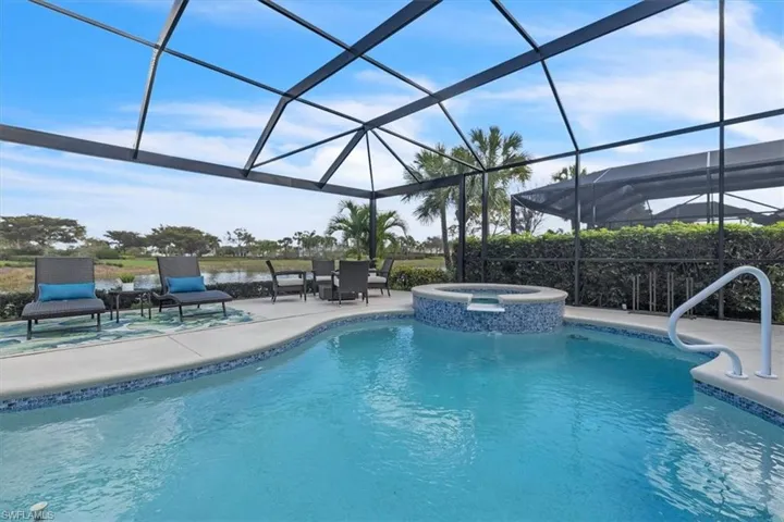 Screened lanai with a freeform pool, integrated spa, and mosaic tile detailing